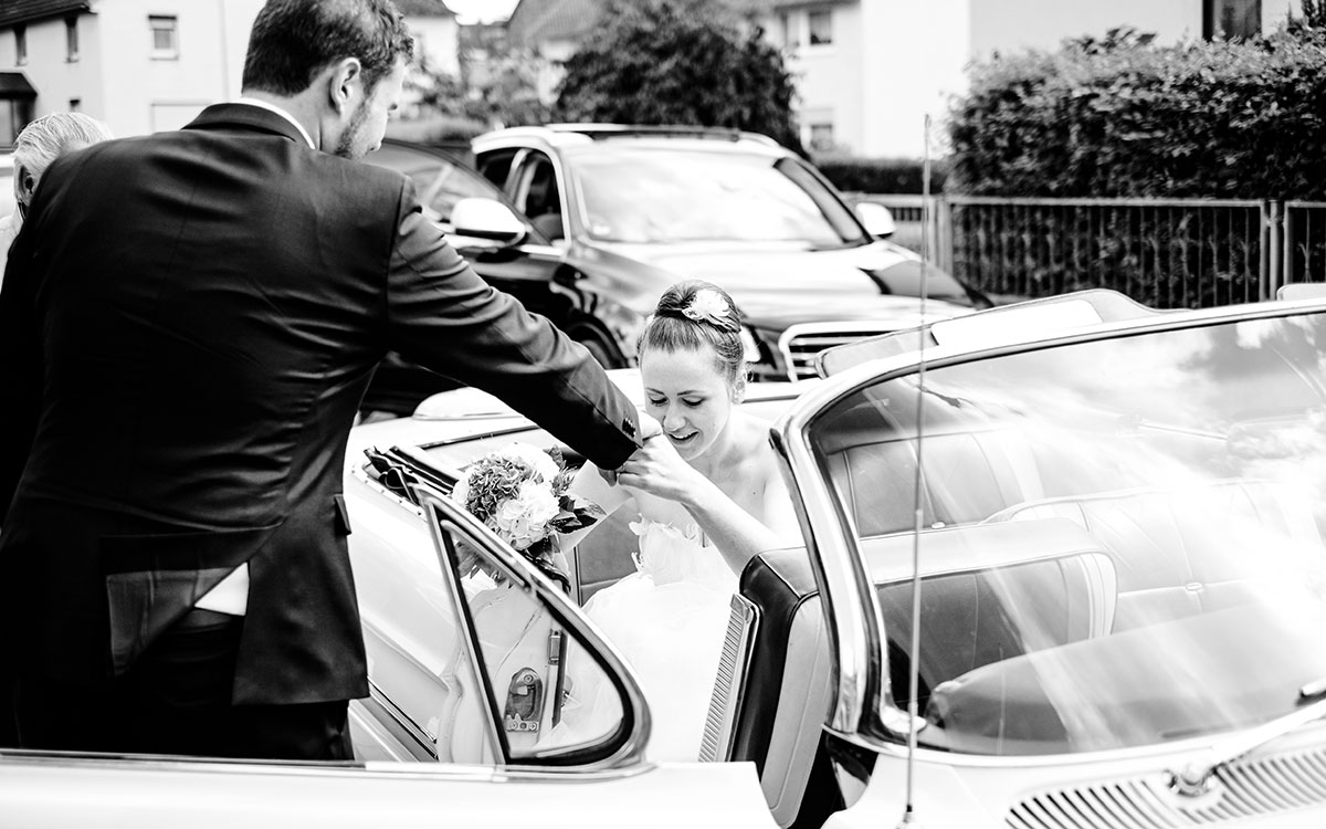 Braut und Bräutigam beim Aussteigen aus dem Hochzeitsauto
