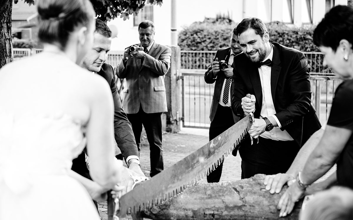 Bräutigam beim Sägen des Baumstamms nach der Trauung